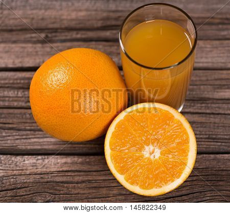 Delicious orange juice with bright irange fruit over wooden background