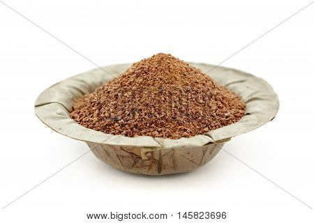 Organic powder of Indian Jujube (Ziziphus mauritiana) in a natural leaf plate. Isolated on white background. Front view.