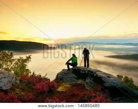 Hiker And Photo Enthusiast Stay With Tripod On Cliff And Takes Photos.
