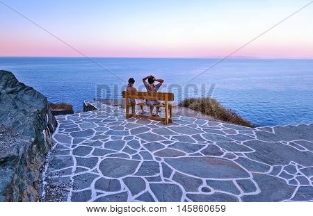 SIFNOS CASTLE CYCLADES GREECE, AUGUST 26 2016: tourists sitting on bench at Sifnos castle Cyclades Greece viewing the Aegean sea. Editorial use.
