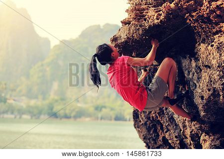 young woman rock climber climbing at seaside mountain rock