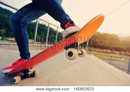closeup of skateboarder legs skateboarding at skatepark