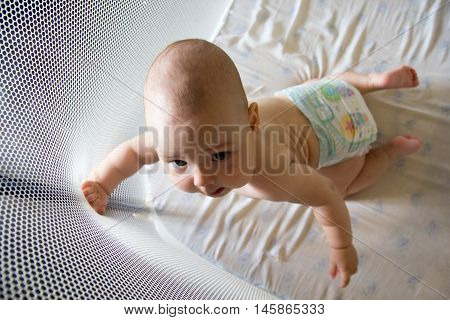 Baby in a diaper in playpen .