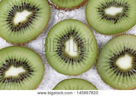 Sliced kiwis with bubble in water on white background.