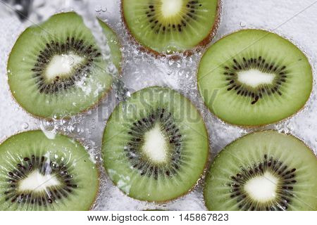 Pour water into sliced kiwis with bubble in water. Selective focus.