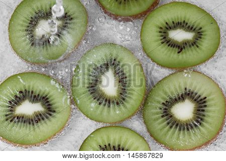 Pour water into sliced kiwis with bubble in water. Selective focus.
