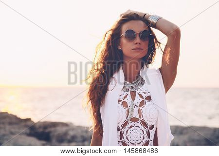 Beautiful boho styled girl wearing white crochet swimsuit with flash tattoo at the beach in sunlight