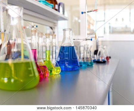 Laboratory table piled tubes with colored liquid colored reagents in flasks and test tubes
