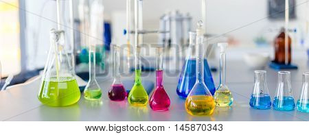 Laboratory table piled tubes with colored liquid colored reagents in flasks and test tubes
