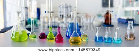 Laboratory table piled tubes with colored liquid colored reagents in flasks and test tubes