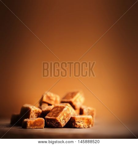 Caramel candies on brown background. Salted caramel pieces and sea salt. Golden Butterscotch toffee caramels. Toffees.