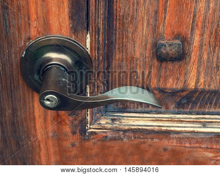 The old metal door handle on the wooden door