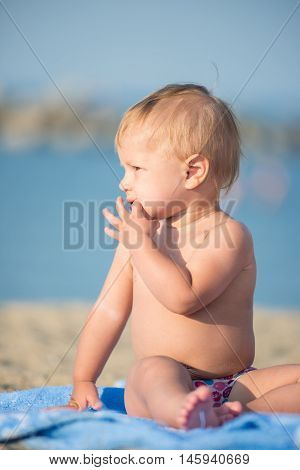 Baby playing with toys on the sandy beach near the sea. Cute little kid in  sand on tropical beach. Ocean coast.