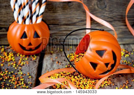 Halloween Jack o Lantern pail on a wooden table with orange ribbons. Halloween party decoration selective focus