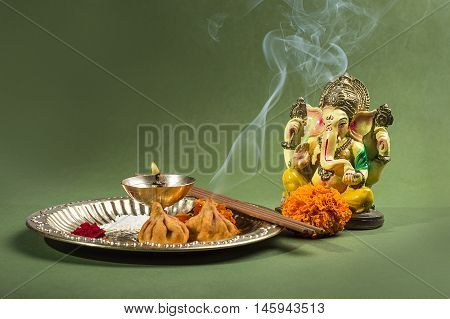 Hindu God Ganesha. Statue of Lord Ganesha. Pooja arrangement on green background.