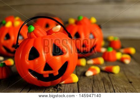 Halloween Jack O Lantern Candy Holders Close Up With Scattered Candy On Rustic Wood