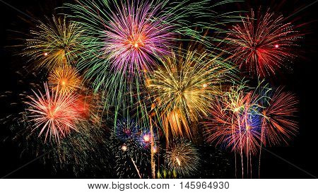 Colorful firework celebration on dark night sky background. Beautiful fireworks show on clear night sky.