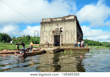 OLD WAT WANG WIWEKARAM SAGKLABURI 12 OCT 2014:Tourists in a long tail boat at the entrance of The Sunken Temple Wat Wang Wiwekaram Kanchanaburi Thailand.
