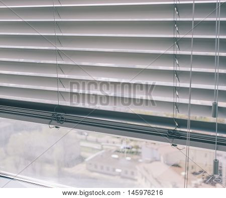 Window blinds on the office window with view on city