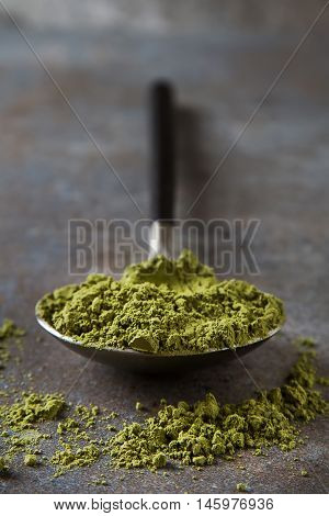 Matcha Tea On A Spoon With Black Handle. Gray Background.
