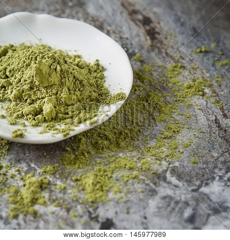 Matcha Tea On A Small White Plate. Gray Background. Top View. Sq
