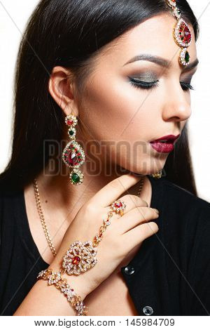 Gorgeous woman with luxurious jewelry close-up. Portrait of beautiful indian princess with ceremonial makeup and finery. Luxury, wealth, pleasure concept