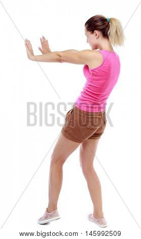 back view of woman pushes wall. backside view of person. Sport blond in brown shorts pushes away someone.