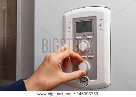 Men hand regulate temperature on 45 degree in control panel of DHW.