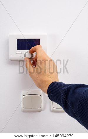 Men hand setting the temperature on control panel of DHW or central heating.