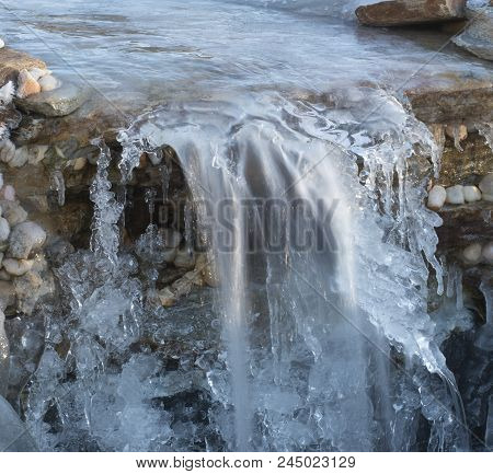 Rocky Cascade With Ice All Over And Water Running Underneath