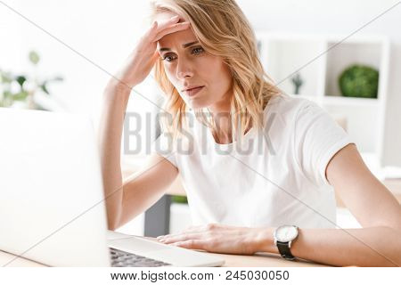 Concetrated businesswoman working on laptop computer while sitting at the office desk
