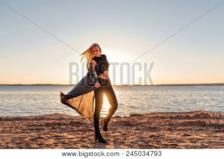 A Girl Of A Sporty Body Steps Into The Dance And Walks Along The Sandy Beach At The Dawn Of The Sun 