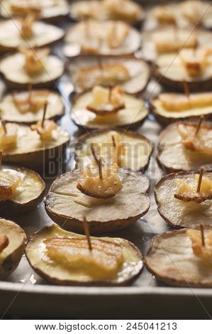 Potato Halves Baked With Bacon Slices On A Baking Sheet