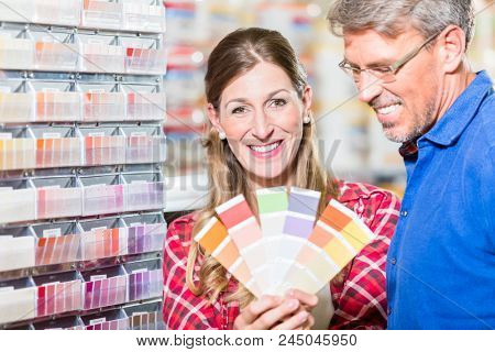 Couple, woman and man, choosing color of wall paint in decoration department of hardware store