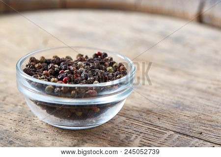 Still Life With Black Pepper Seeds In Glass Jar On Wooden Barrel, Close-up, Shallow Depth Of Field. 