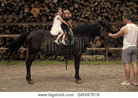Hippotherapy. Man Teach Girls Ride Horse On Wood Stack Background. Learning, Playing, Entertainment,