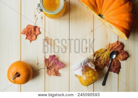 Top View Of Autumn Still Life Of Organic Pumpkin, Pumpkin Jam In A Jar, Maple Leaves And Spoon On Na