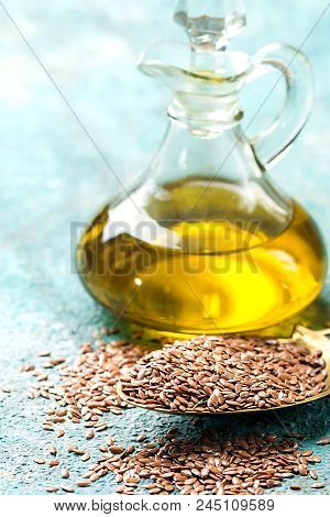 Flax Seeds And Linseed Oil In A Glass Jug Over Blue Background, Healthy Diet With Omega 3 Fatty Acid