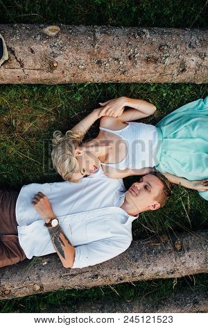 Couple In Love Walking Near Logs In The Mountains.
