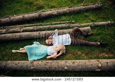 Couple In Love Walking Near Logs In The Mountains.