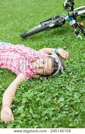 Girl In The Park  Sittind Down On The Grass Next To Her Bicycle