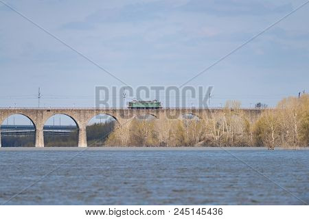 The Train Travels Along The Railway Bridge Across The River