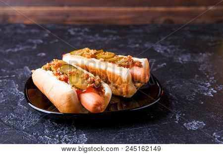 Image Of Hotdogs On Black Plate At Table