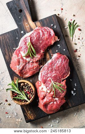 Beef Steak Rib Eye On A Cutting Board With Rosemary And Spices. Fresh Meat Uncooked.