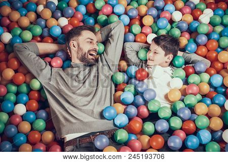 Top View. Joyfull Dad And Son In Pool With Balls Watching Each Other. Rest, Holiday, Leisure. Spendi