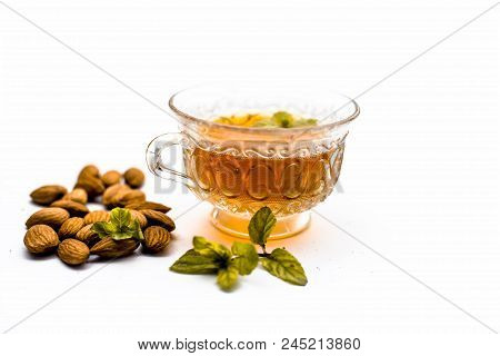 Beneficial And Essential Oil Of Badam Or Almonds With Its Beneficial Tea In A Transparent Cup Isolat