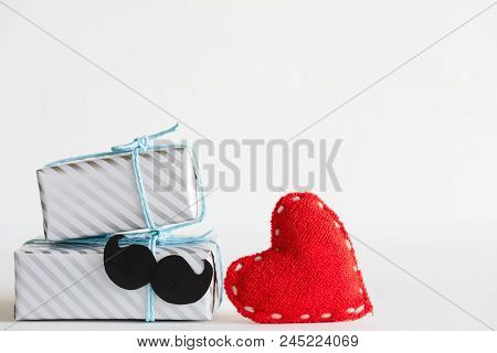 Happy Fathers Day Concept. Stack Of Beautiful Gift Box With Mustache And Handmane Red Heart On White