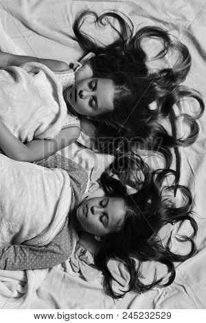 Girls On White And Pink Bed Sheets Background. Kids With Motionless Faces And Heart Shaped Hair Lie 