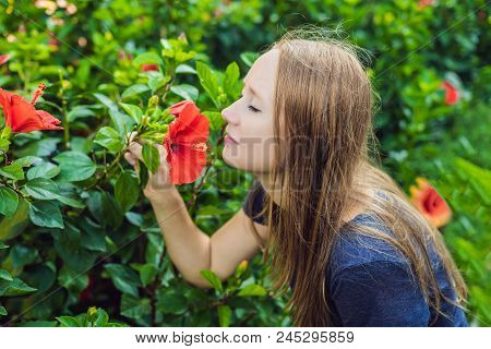 Young Woman Sniffing Hibiscus In The Park.