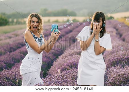 Sister having fun with bubble wand outdoor. Soap bubble fight. 